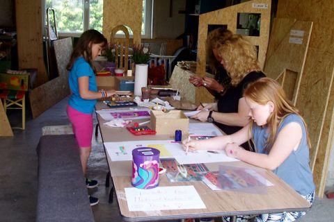 Zwei Betreuerinnen und zwei Mädchen beim gemeinsamen Zeichnen und Malen